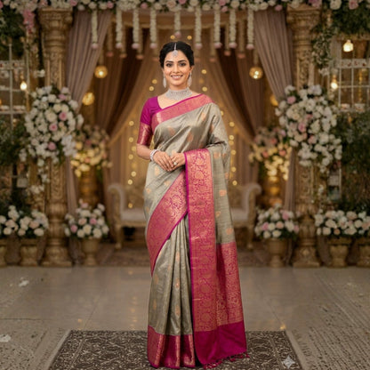Woman in a traditional saree standing in a decorated indoor setting with flowers and lights.