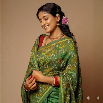 Woman wearing a green saree with a floral design on a beige background