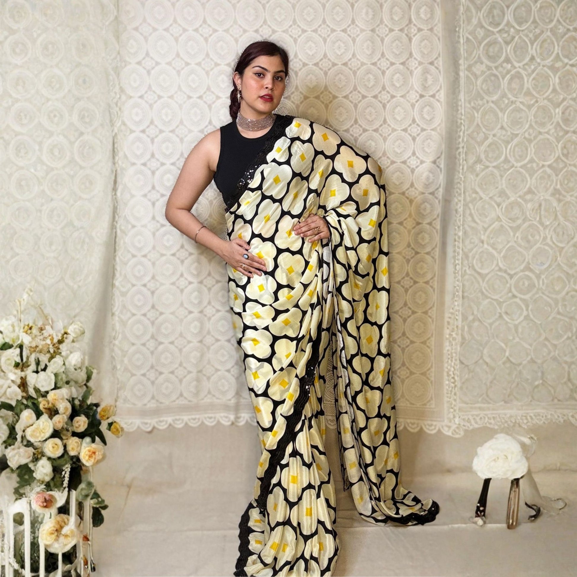 Woman wearing a black and white floral saree against a white background