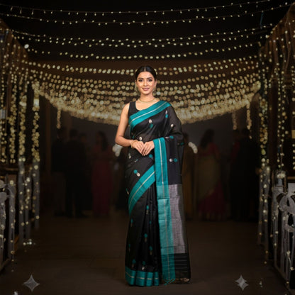 Woman in a black and blue saree standing in front of string lights