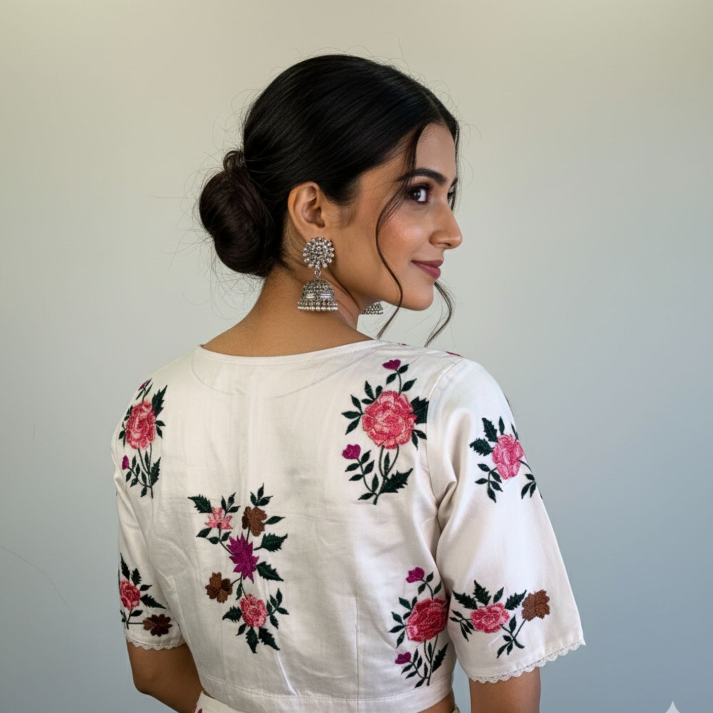 Woman wearing a white blouse with floral embroidery on a plain background