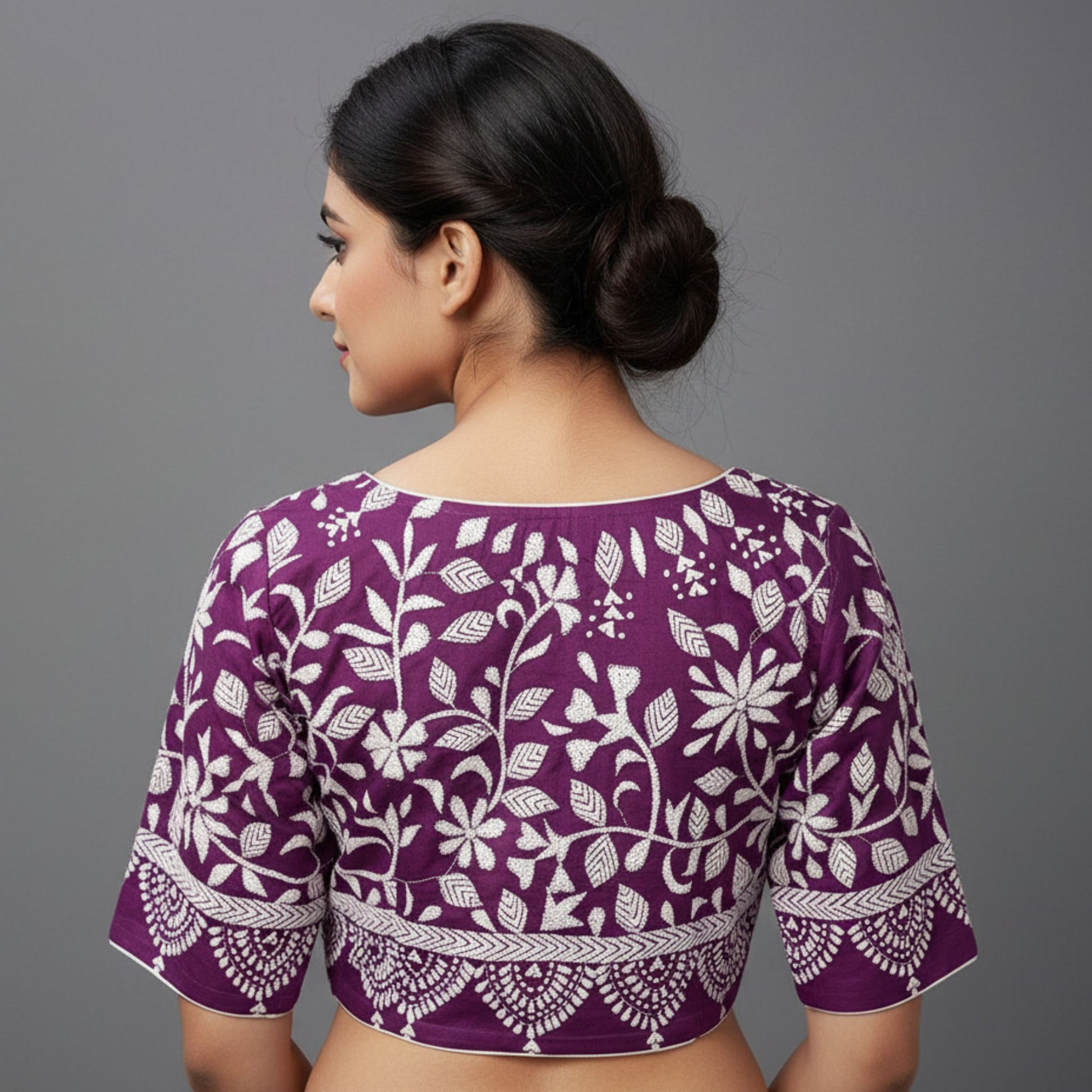 Woman wearing a purple blouse with white floral patterns on a gray background
