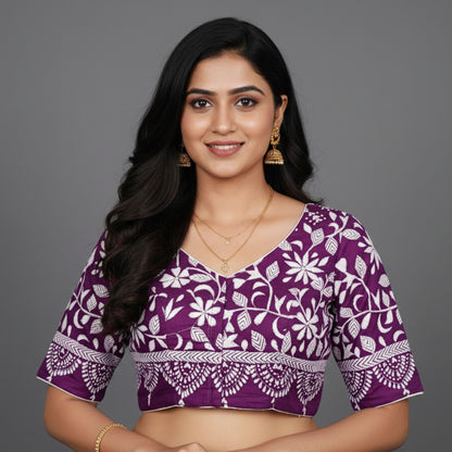 Woman wearing a purple blouse with white floral patterns on a gray background