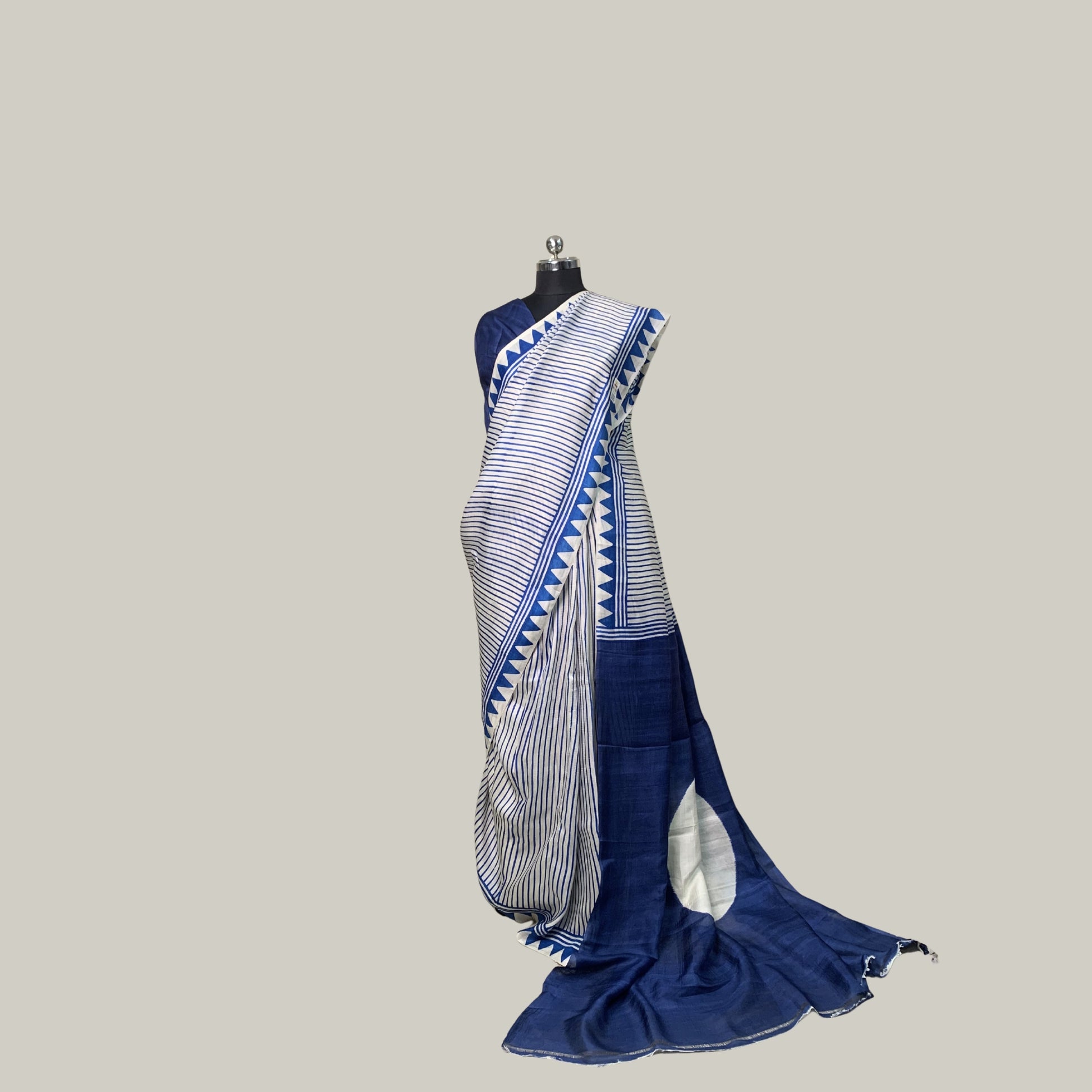 A blue and white striped saree draped on a black mannequin torso against a solid light gray background.