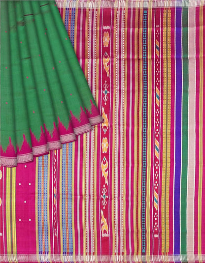 A close-up of a patterned fabric, likely a saree, featuring a solid green drape on the left with a pink and magenta border, and a highly detailed multicolor striped and geometric woven body on the right.Close-up flat lay of Kumbha motifs and weave.