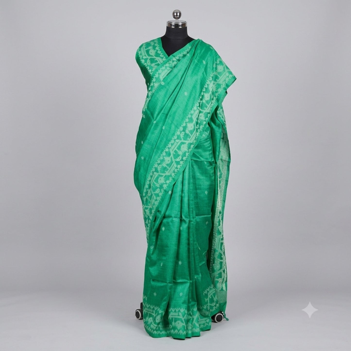 A green silk saree with a white printed border and motifs, draped on a black mannequin against a light gray background.