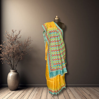 Yellow saree with a floral pattern draped over a mannequin against a dark wall.